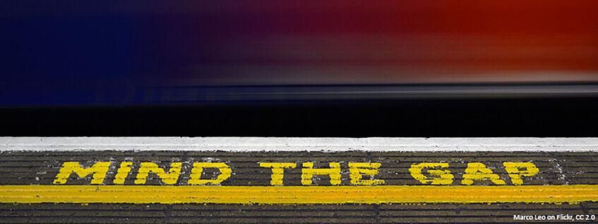 Foto von einem Bahnsteig, auf dem in gelber Schrift "Mind the gap" steht